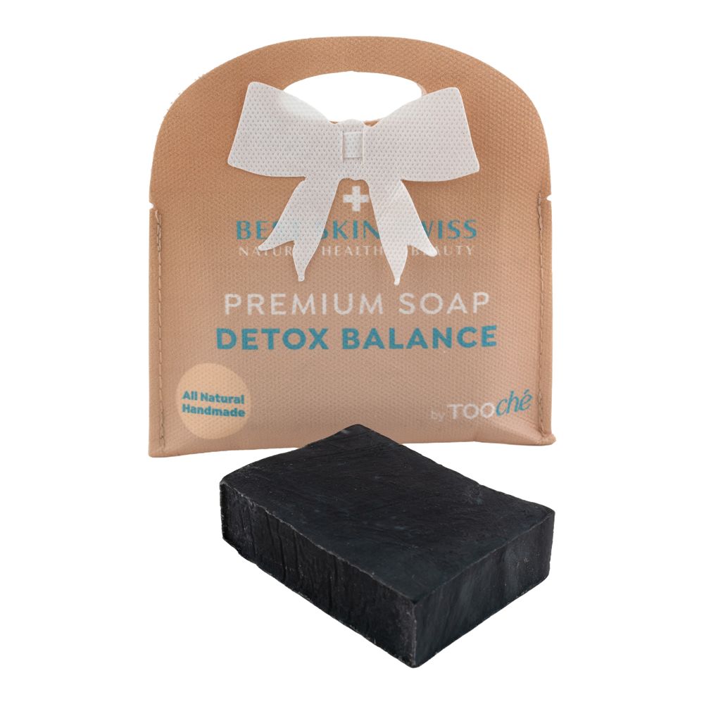 Schwarze Seife vor Verpackung mit Schleife. Verpackung mit Aufschrift: Premium Soap Detox Balance. Marke: Tooché.