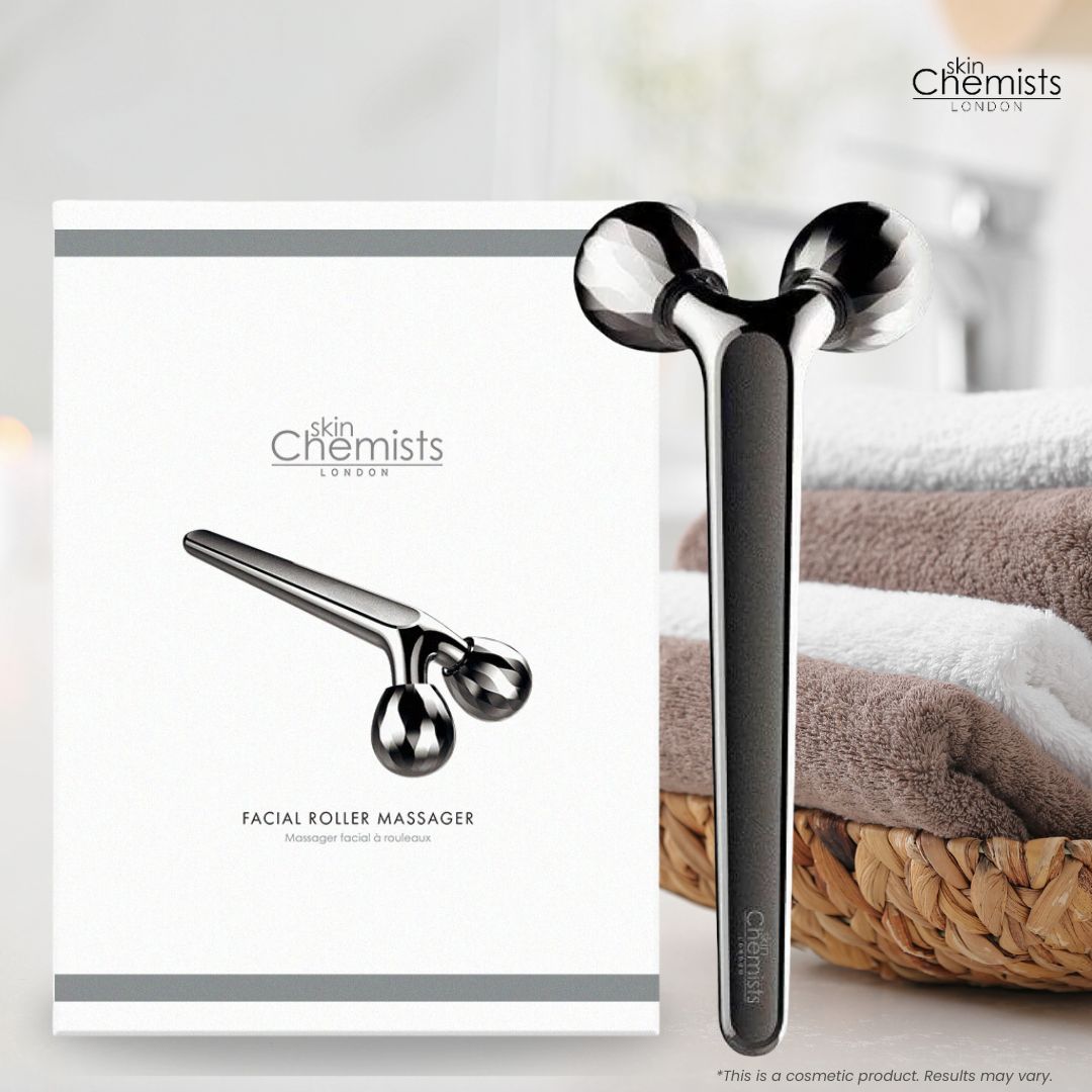Gesichts-Rollenmassagegerät neben Verpackung und Handtüchern. Produktbezeichnung und Logo sichtbar.