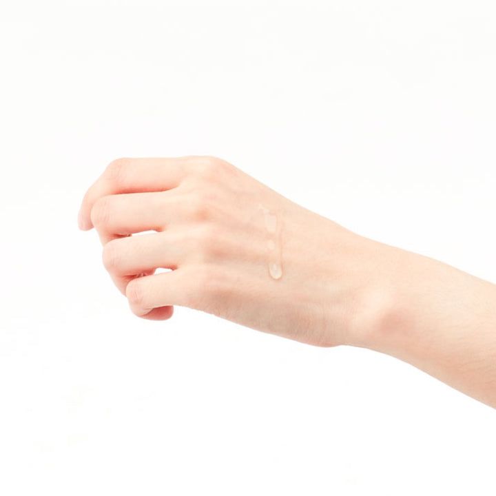 Hand mit Tropfen einer klaren Flüssigkeit. Hintergrund weiß. Keine weiteren Details.