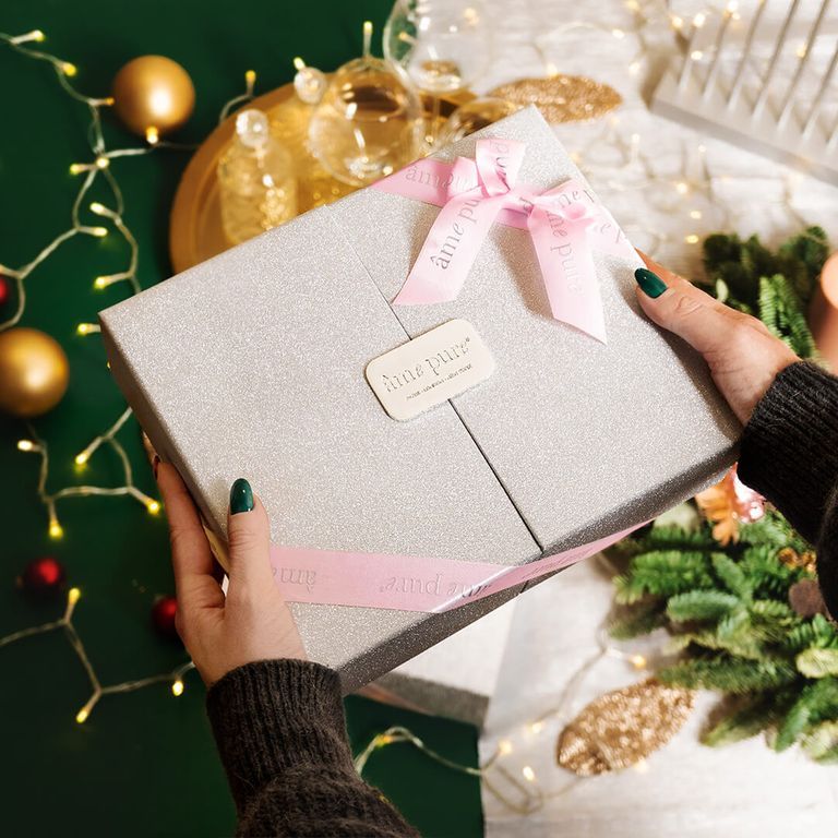 Eine glitzernde Geschenkbox mit rosa Schleifen, "âme pure" Logo auf einem Etikett.