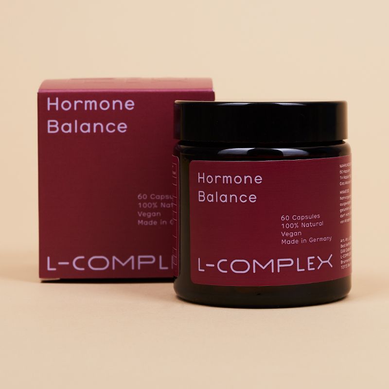 Braune Dose und Schachtel mit rotem Etikett. Aufschrift: Hormone Balance, 60 Kapseln, L-COMPLEX.