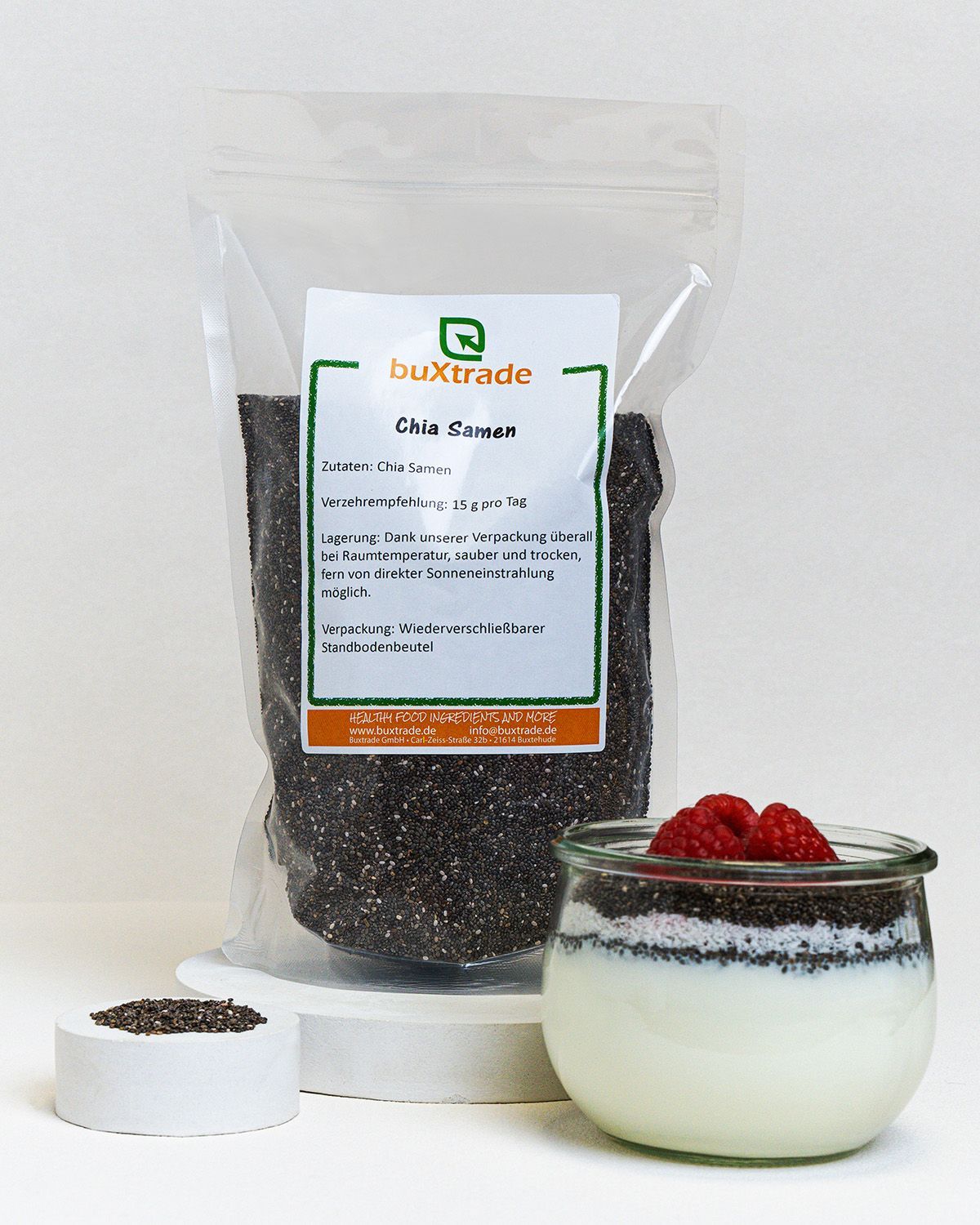 Beutel mit Chia Samen, daneben ein Glas mit Joghurt und Himbeeren. Marke: buXtrade.