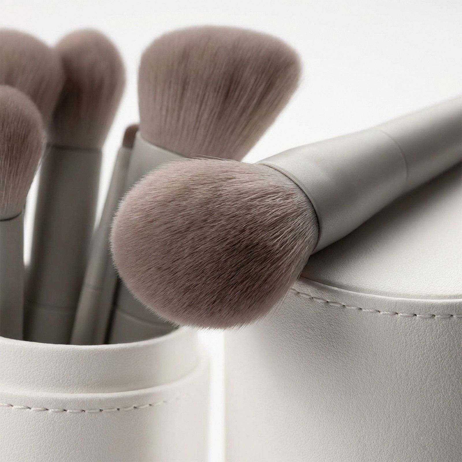 Set von grauen Make-up-Pinseln mit weichen Borsten in einem weißen Halter.