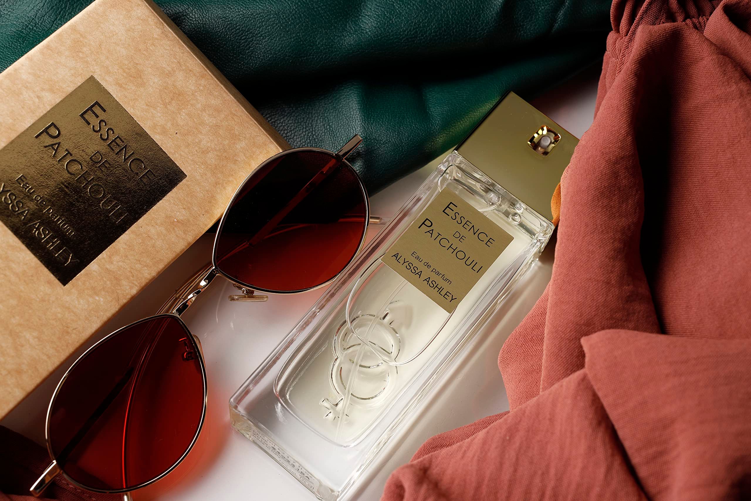 Alyssa Ashley Essence de Patchouli Eau de Parfum Flakon, Sonnenbrille und Stoff.
