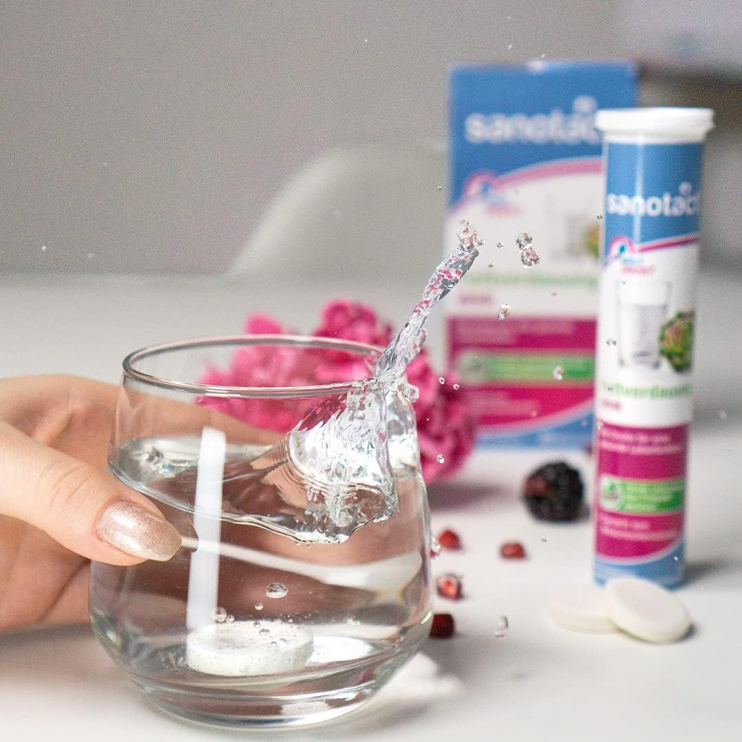 Glas Wasser mit Brausetablette, die sich auflöst. Daneben eine Packung und eine Tube Sanotact Fettverdauung Drink Brausetabletten.
