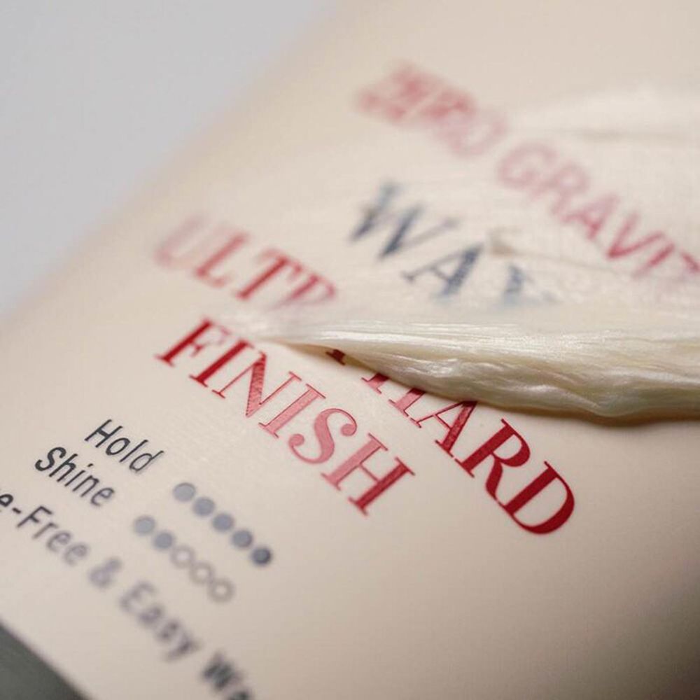 Nahaufnahme der Produkttextur. Text: Ultra Hard Finish, Hold, Shine. Transparente Folie liegt auf dem Text.
