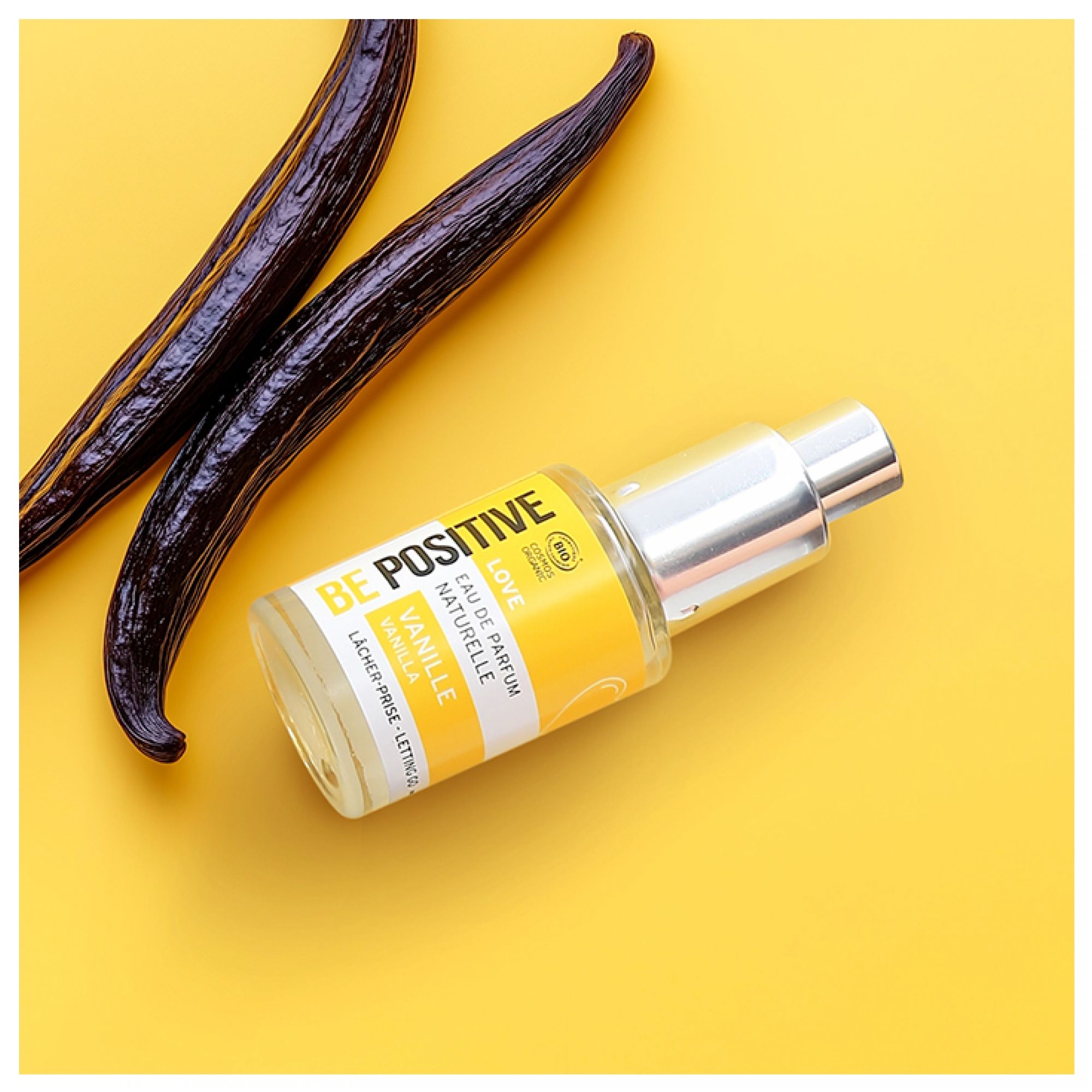 Acorelle Be Positive Eau de Parfum Love Vanille neben zwei Vanilleschoten auf gelbem Hintergrund.