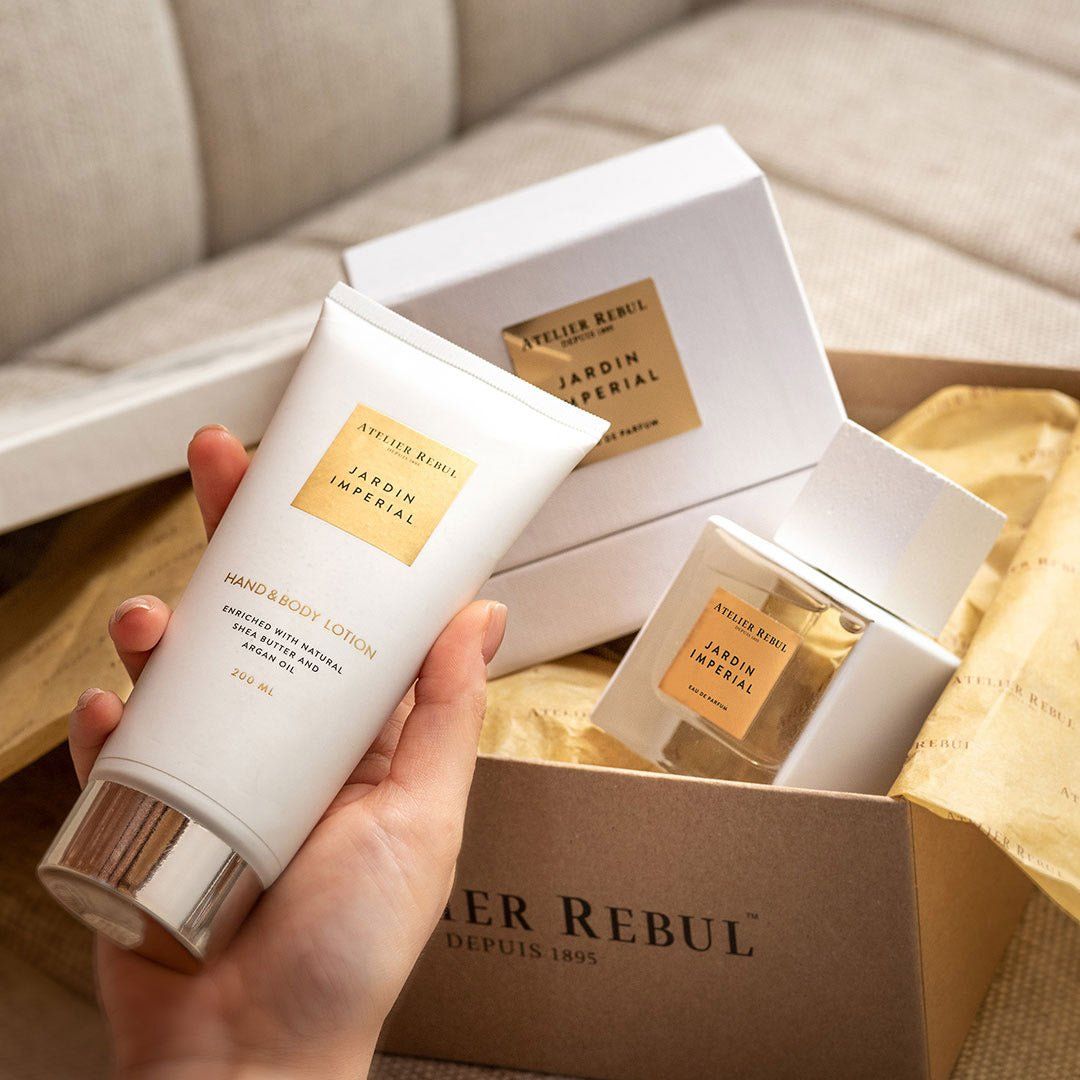 Hand hält Hand- und Bodylotion und Parfumflasche. Beide Produkte in einer Geschenkbox. Aufschrift Jardin Imperial.