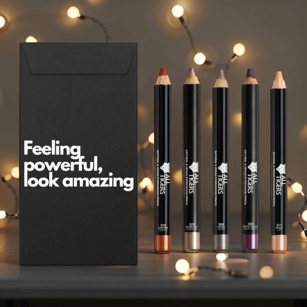 Fünf Augenstifte neben schwarzem Umschlag mit Text. Stifte in verschiedenen Farben, mit Logo und Produktbezeichnung.