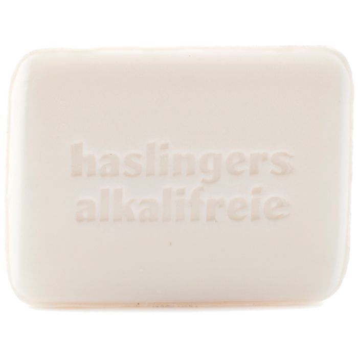 Rechteckige Seife mit geprägtem Schriftzug "haslingers alkalifreie". Helle Farbe, abgerundete Kanten.