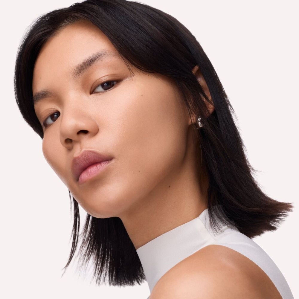 Porträt einer Frau mit dunklen Haaren. Sie trägt Ohrringe. Ihr Teint ist ebenmäßig.