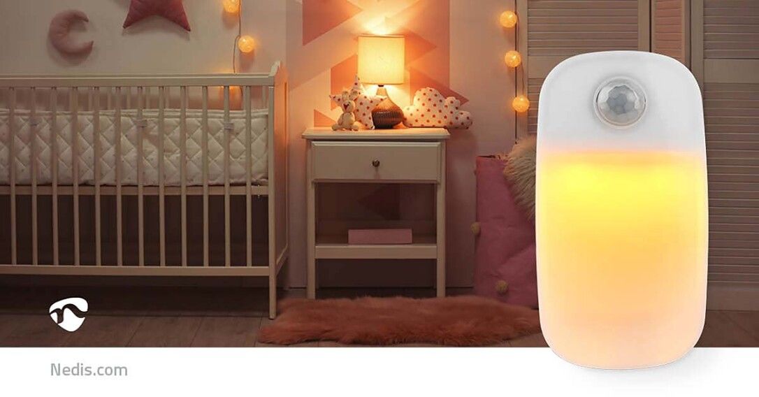Nachtlicht mit Bewegungssensor, leuchtend. Im Hintergrund ein Kinderzimmer mit Bettchen und Nachttisch.