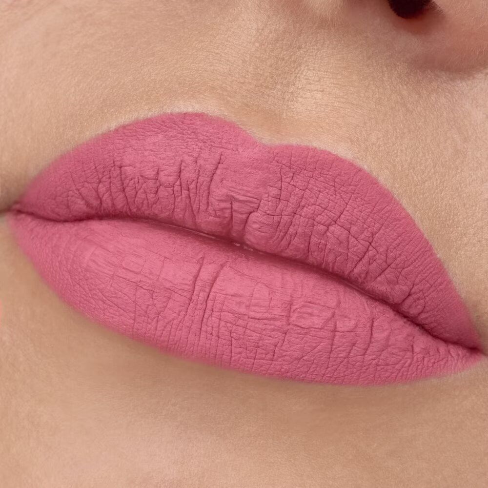 Nahaufnahme von Lippen mit rosa Lippenstift. Die Lippen sind voll und haben eine matte Textur.