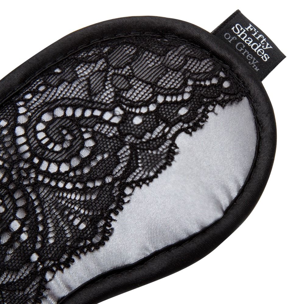 Nahaufnahme der Augenmaske. Schwarze Spitze auf Satin. Label mit "Fifty Shades of Grey".