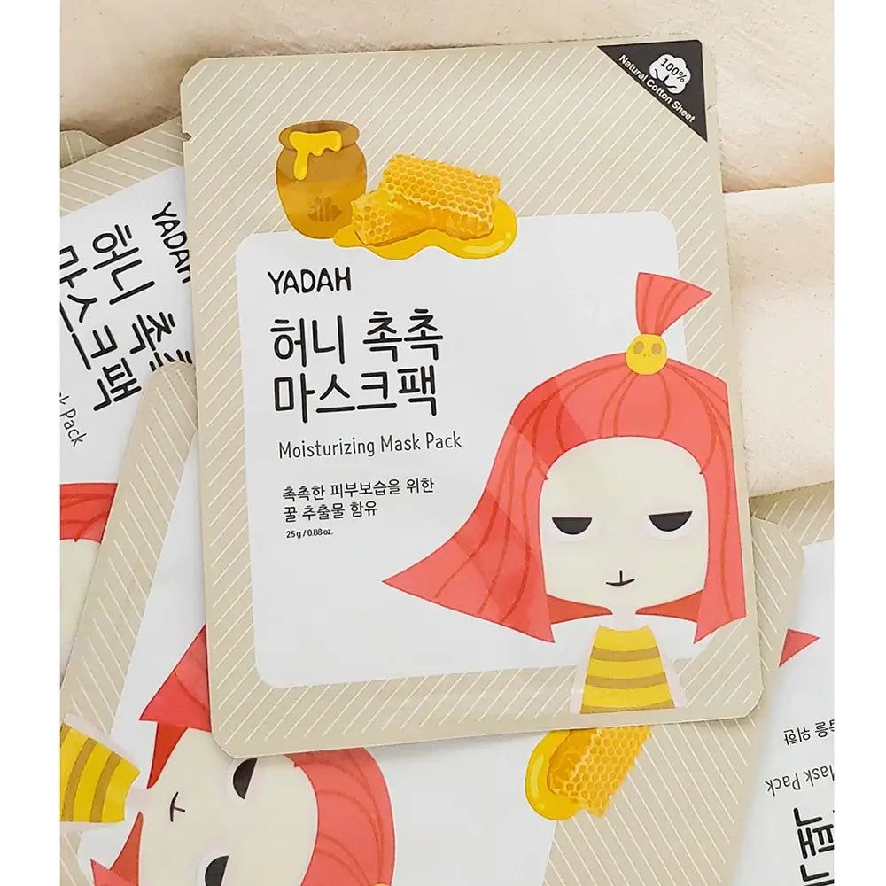 Mehrere YADAH-Gesichtsmasken. Verpackung mit Honig-Illustration und koreanischem Text. Aufschrift: Moisturizing Mask Pack.