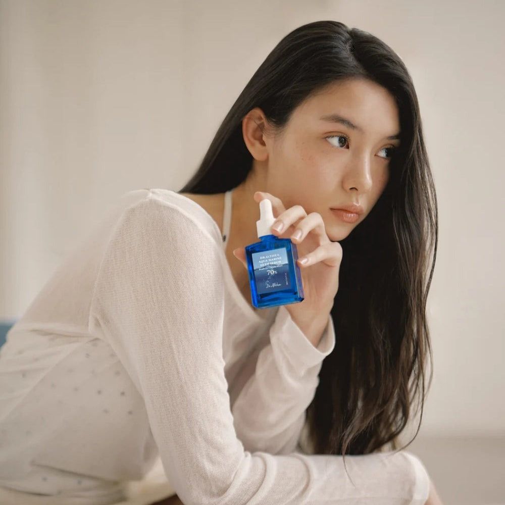 Frau hält eine blaue Serumflasche. Aufschrift: Dr. Althea Aqua Marine Deep Serum, 70%.