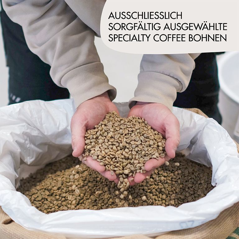 Hände halten grüne Kaffeebohnen. Text: Ausschließlich sorgfältig ausgewählte Specialty Coffee Bohnen.