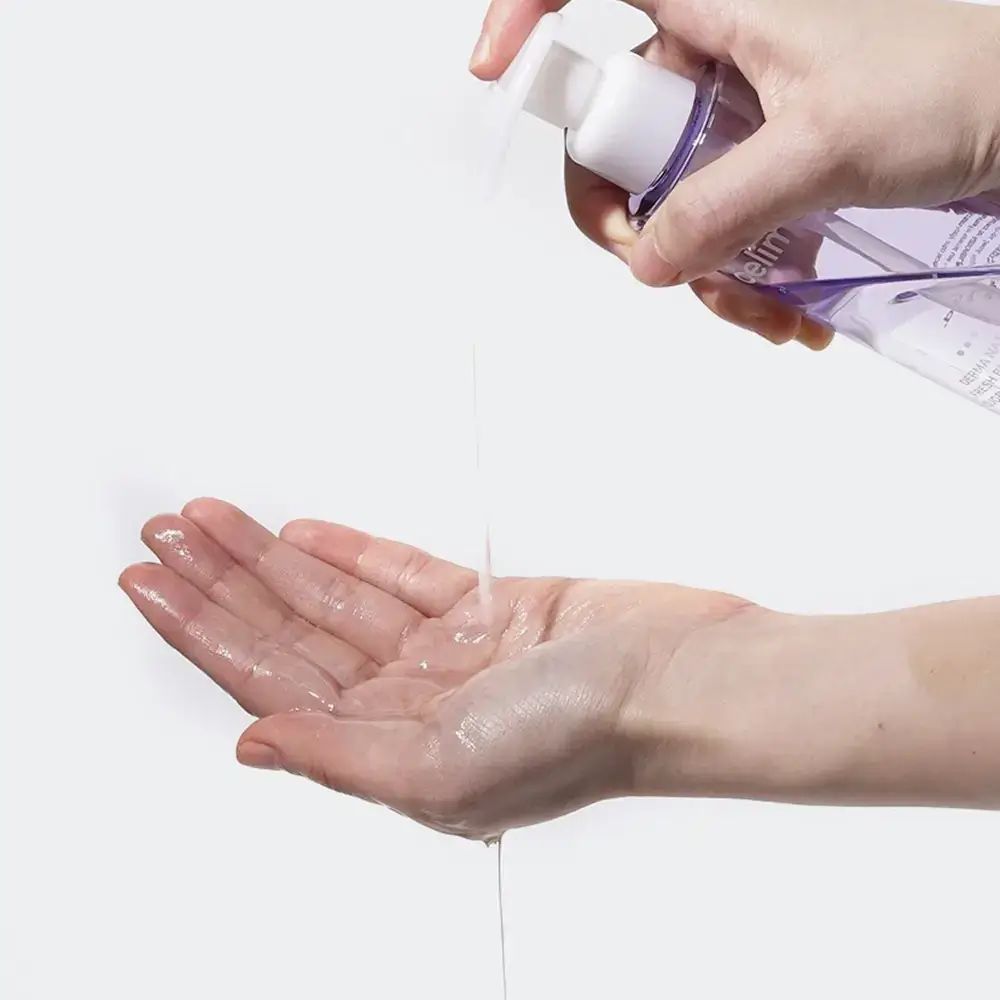 Hand, die Öl aus einer Flasche mit Pumpkopf empfängt. Produkt nicht vollständig sichtbar.