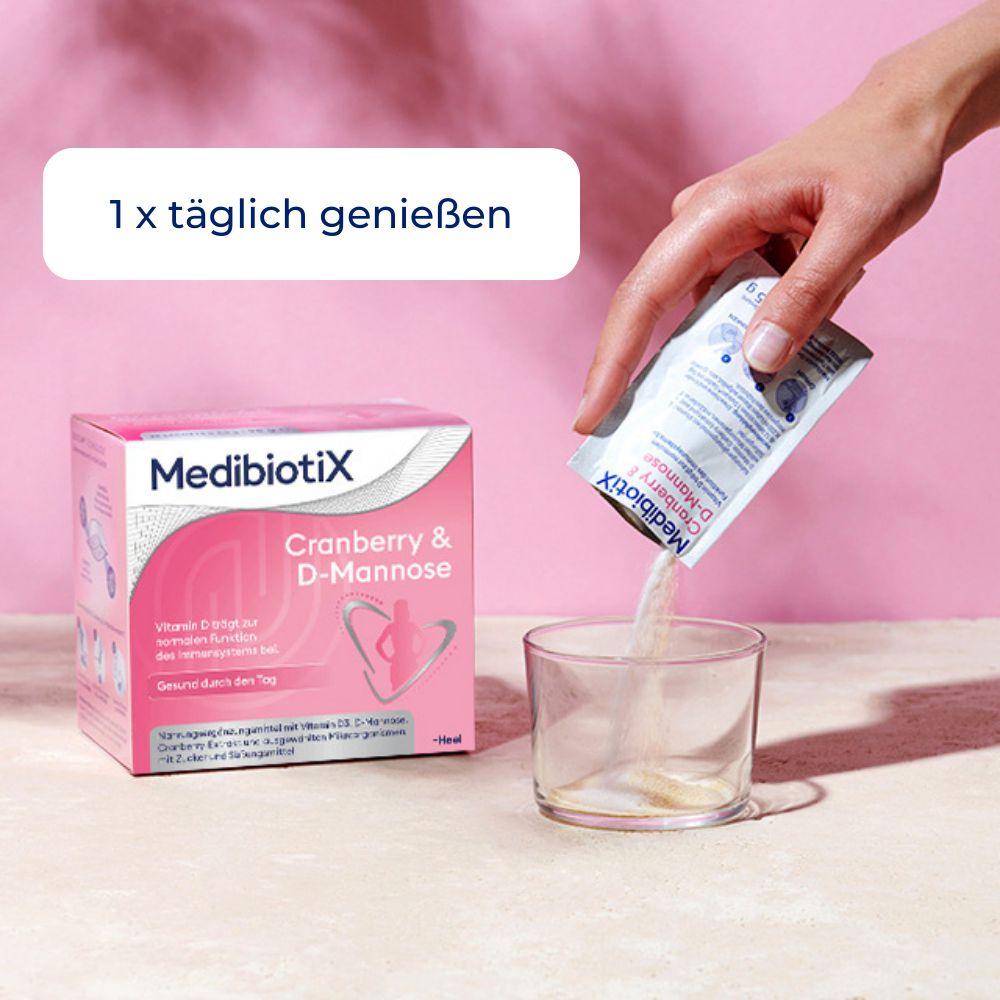 Hand gießt Inhalt eines Päckchens "MedibiotiX Cranberry & D-Mannose" in ein Glas. Text: "1 x täglich genießen".