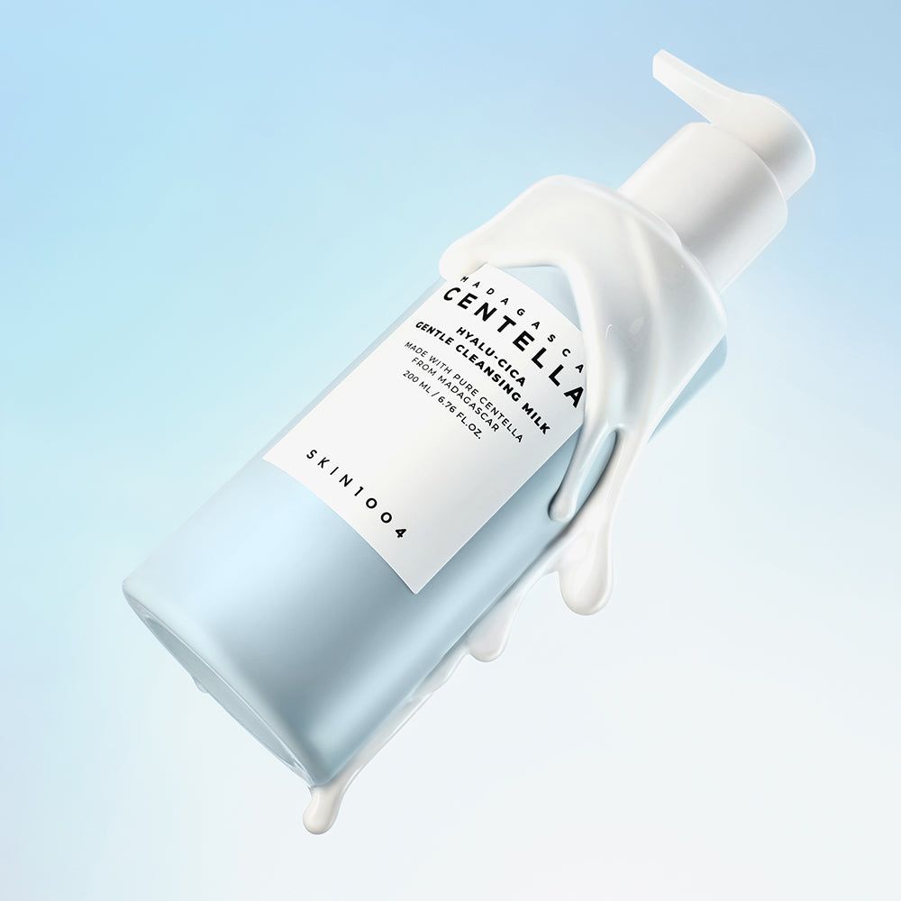 Hellblaues Fläschchen mit weißem Pumpkopf, umgeben von Creme. Aufkleber mit Text: MADAGASCAR CENTELLA HYALU-CICA GENTLE CLEANSING MILK. SKIN1004.
