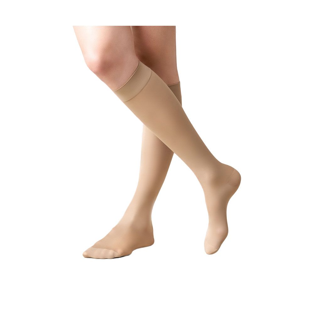 Beige Kniestrümpfe. Kompressionsstrümpfe, getragen von einer Person. Zehen- und Fersenbereich sichtbar.