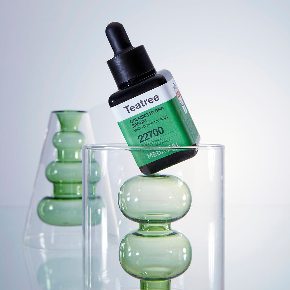 Serumflasche mit schwarzem Deckel in einem grünen Glas. Aufschrift: Teatree Calming Hydra Serum, 22700, MEDIHEAL.