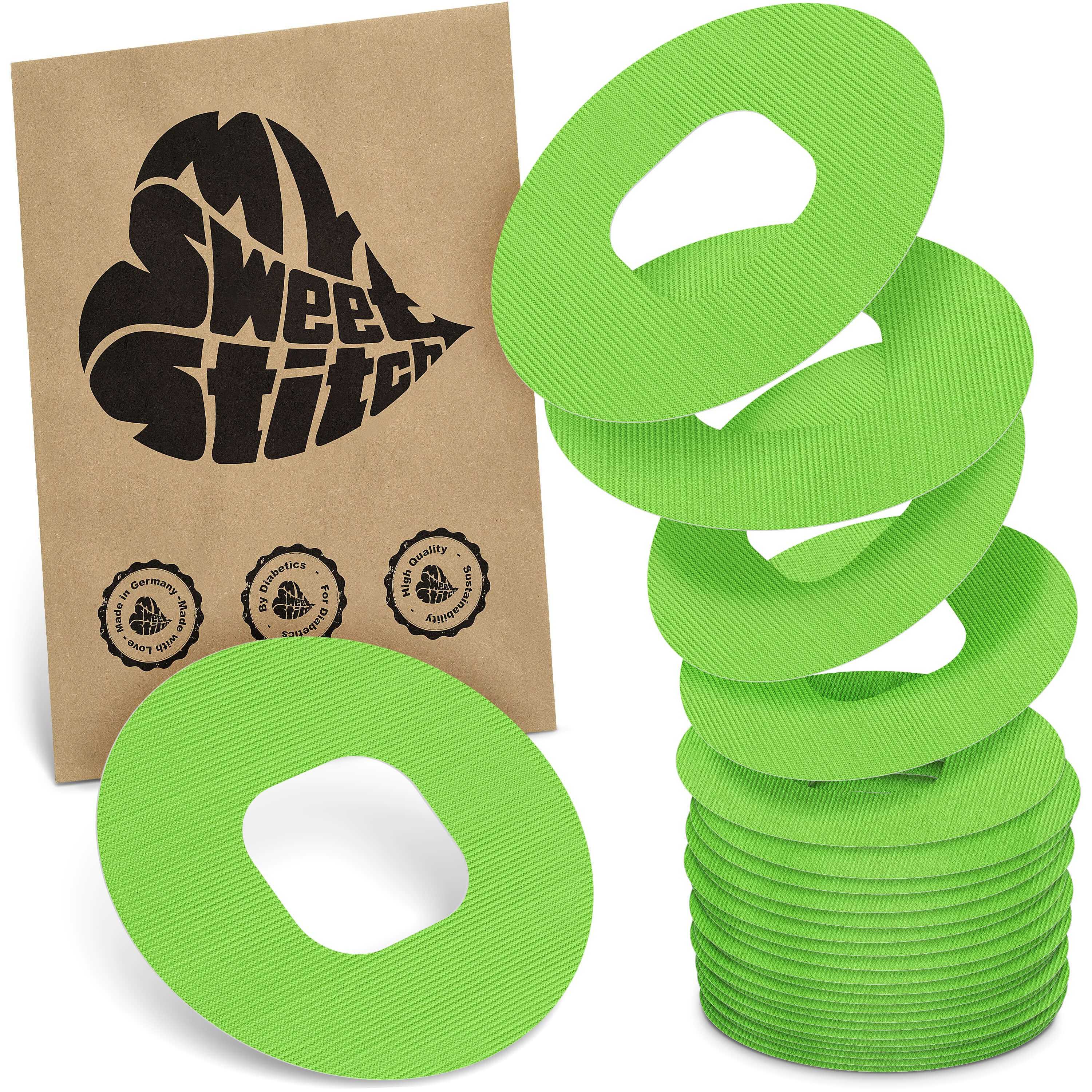 Grüne, ringförmige Pflaster mit Loch in der Mitte. Neben einer braunen Verpackung mit Logo und Qualitätssiegeln gestapelt.