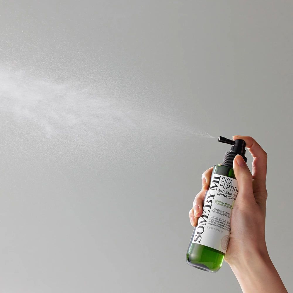 Eine Hand sprüht eine grüne Flasche mit schwarzem Sprühkopf. Aufschrift: Cica Peptide Anti Hair Loss Derma Scalp Tonic.