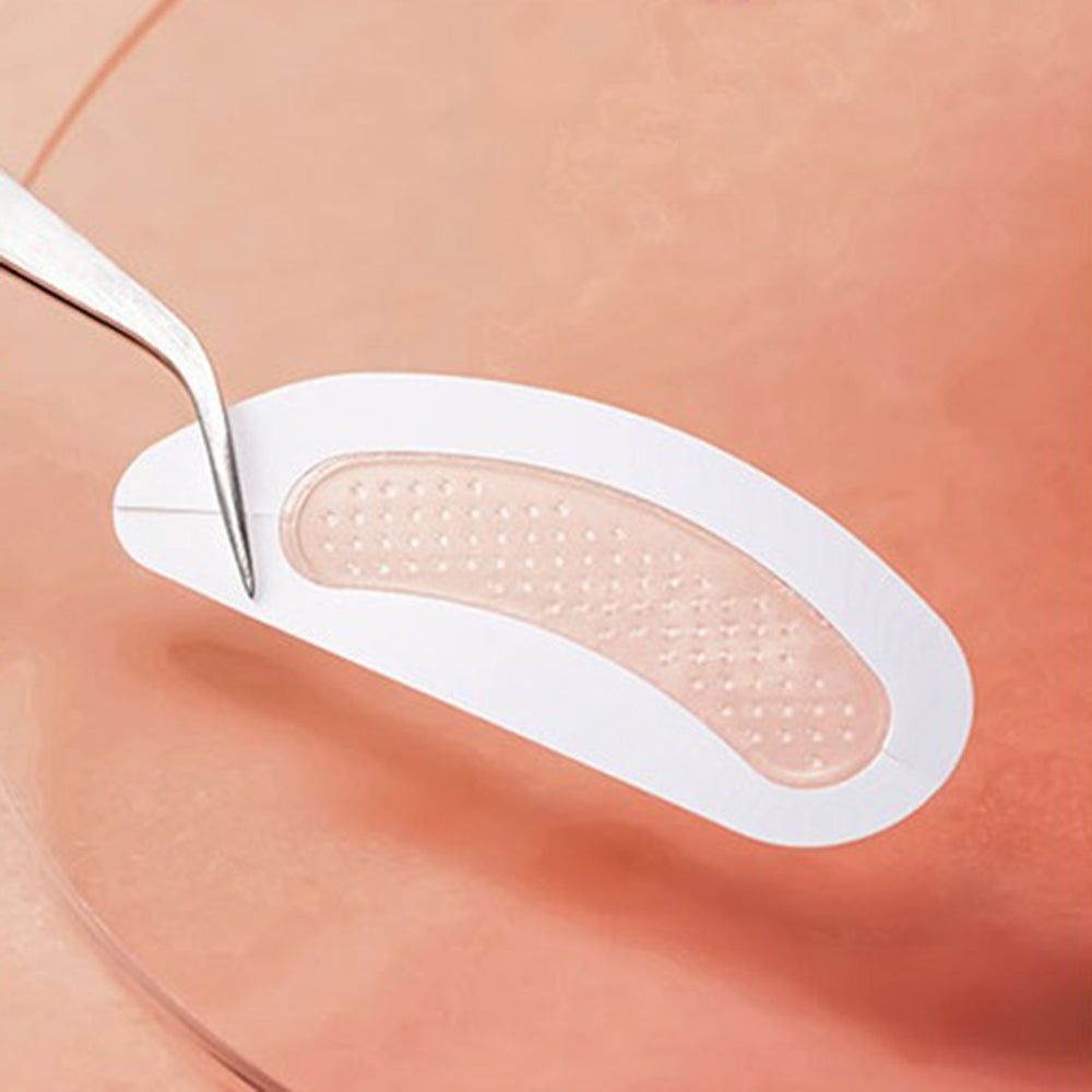 Ein Pflaster wird mit einer Pinzette von einem Trägerpapier abgehoben. Das Pflaster ist oval und hat kleine Erhebungen.