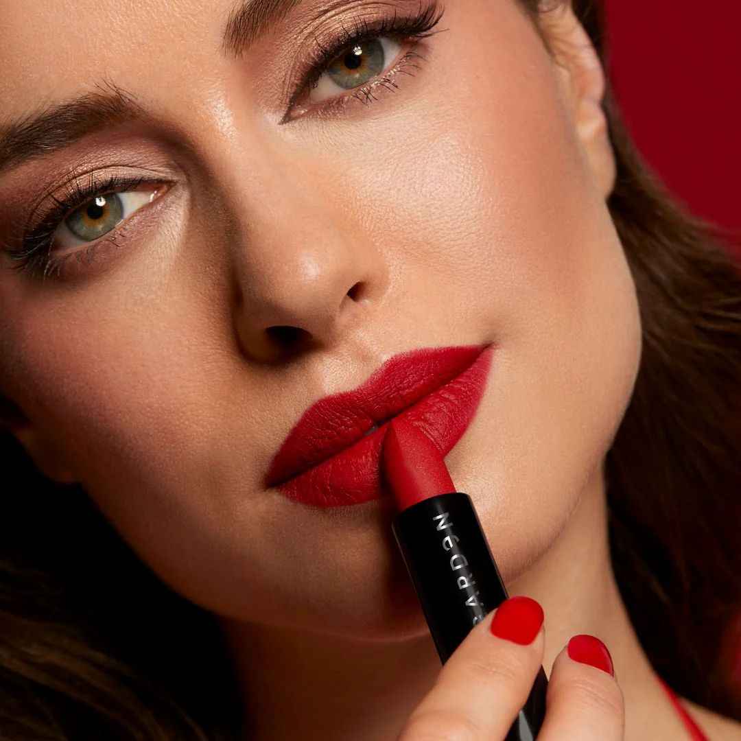 Frau trägt roten Lippenstift auf. Schwarzer Lippenstift-Stift, Marke sichtbar.
