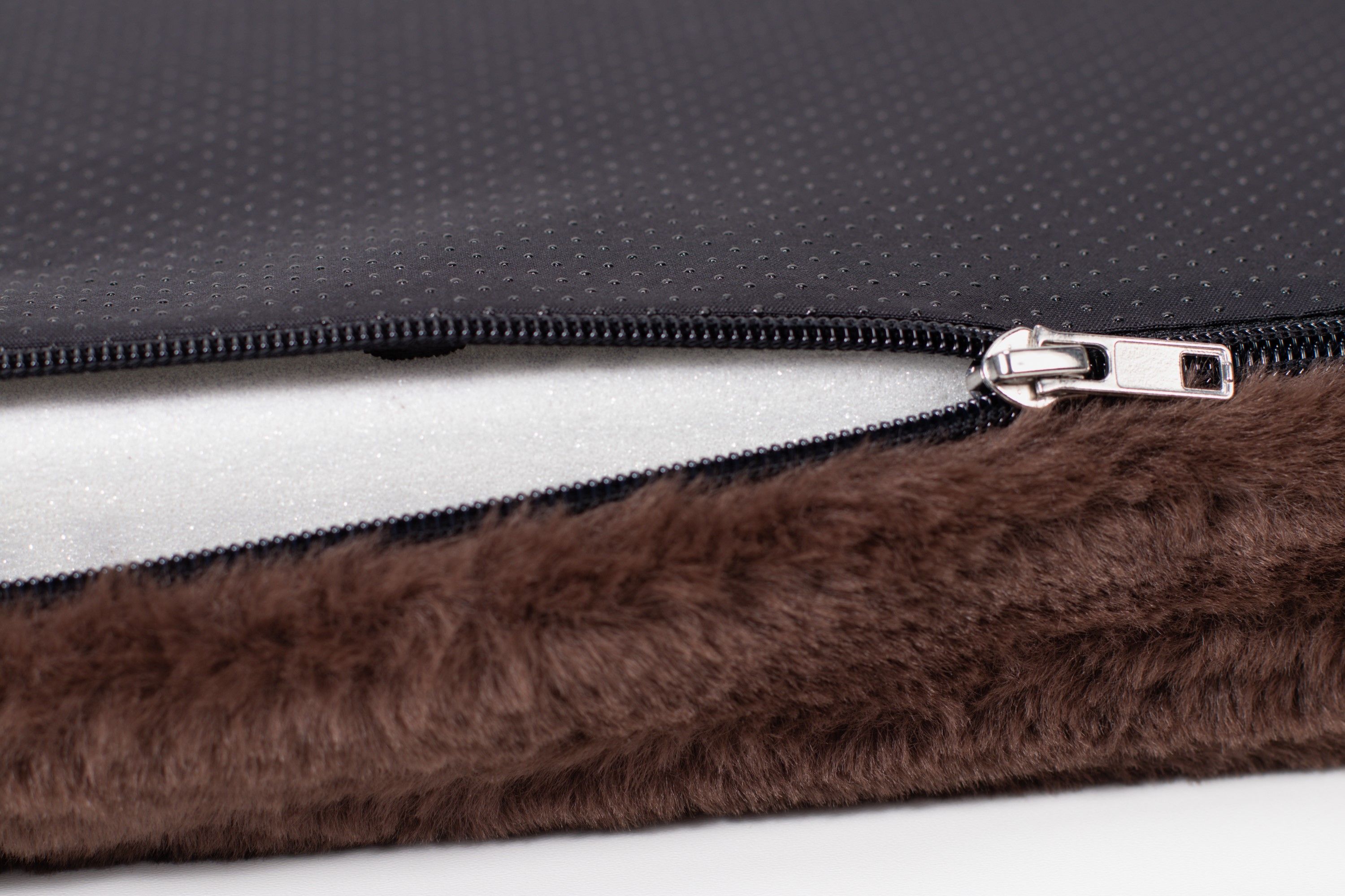 Detailansicht einer Hundematratze mit Reißverschluss. Brauner Plüschstoff und schwarzer Stoff sind sichtbar.