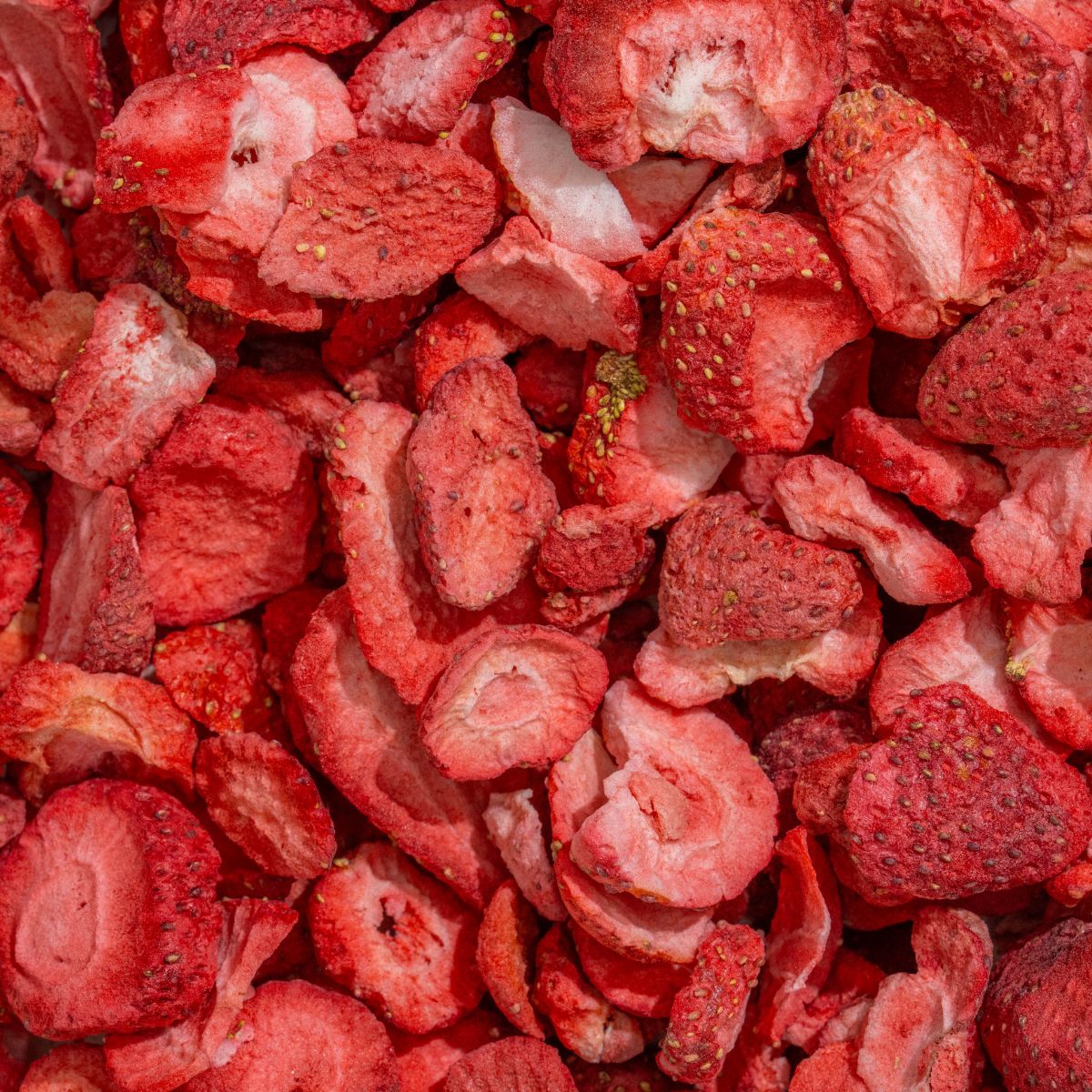 Nahaufnahme von gefriergetrockneten Erdbeerstücken. Rote Farbe, unregelmäßige Formen.