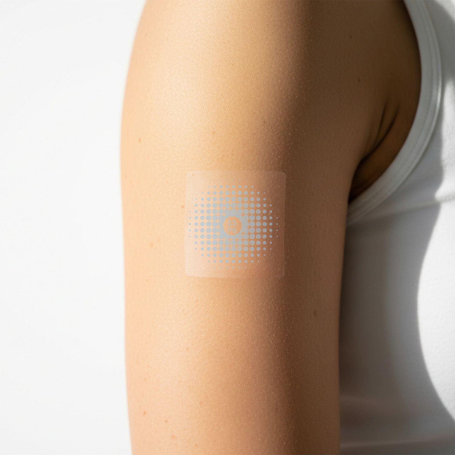 Ein transparentes, quadratisches Pflaster auf einem Arm. Das Pflaster hat ein blaues Punktmuster.