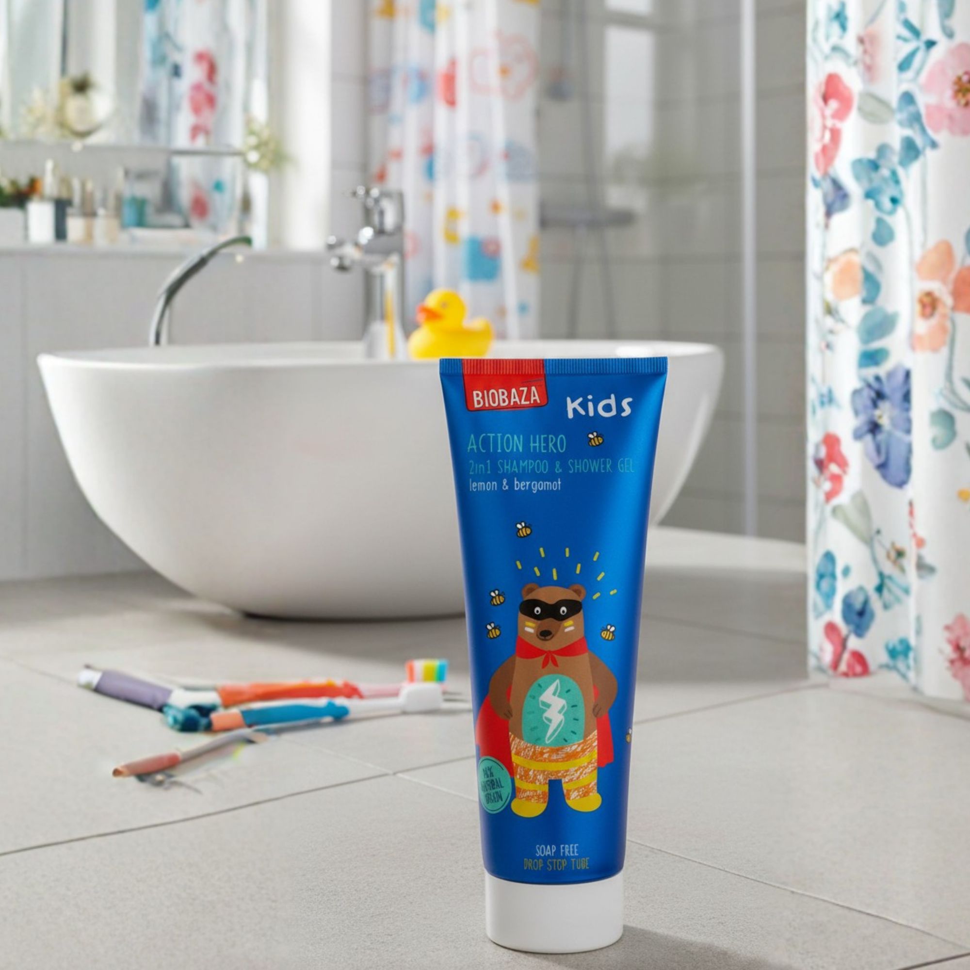 Blau-weiße Tube mit Produktaufdruck: Biobaza Kids Action Hero. Aufdruck: Bär mit Umhang. Im Badezimmer, neben Badewanne und Zahnbürsten.