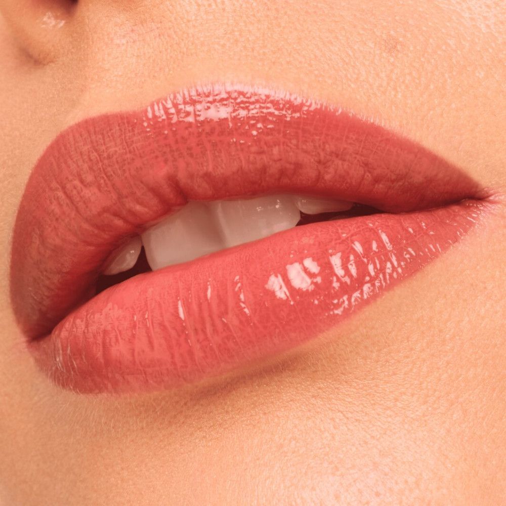 Nahaufnahme von Lippen mit Catrice Colour Glaze Lip Tint. Die Lippen sind glänzend und in einem rosafarbenen Farbton.
