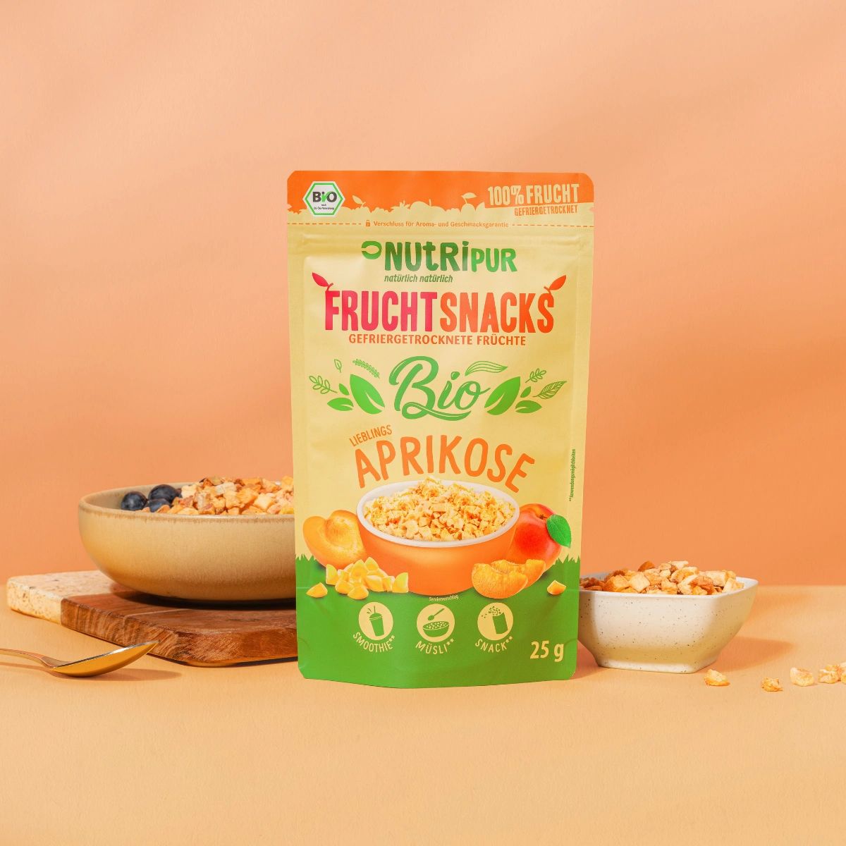 Verpackung NutriPur Fruchtsnacks, gefriergetrocknete Bio-Aprikosen. Schale mit Aprikosen und Blaubeeren. Kleine Schale.