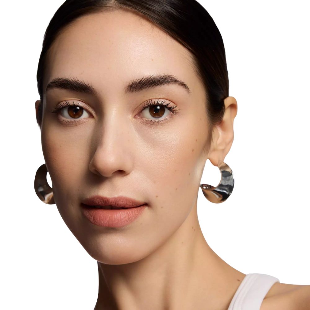 Porträt einer Frau mit hellbraunen Lippen. Sie trägt silberne Ohrringe.