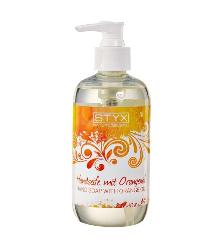 Transparente Flasche mit Spender. Etikett mit STYX-Logo und Schriftzug Handseife mit Orangenöl. Orangefarbene und gelbe Verzierungen.