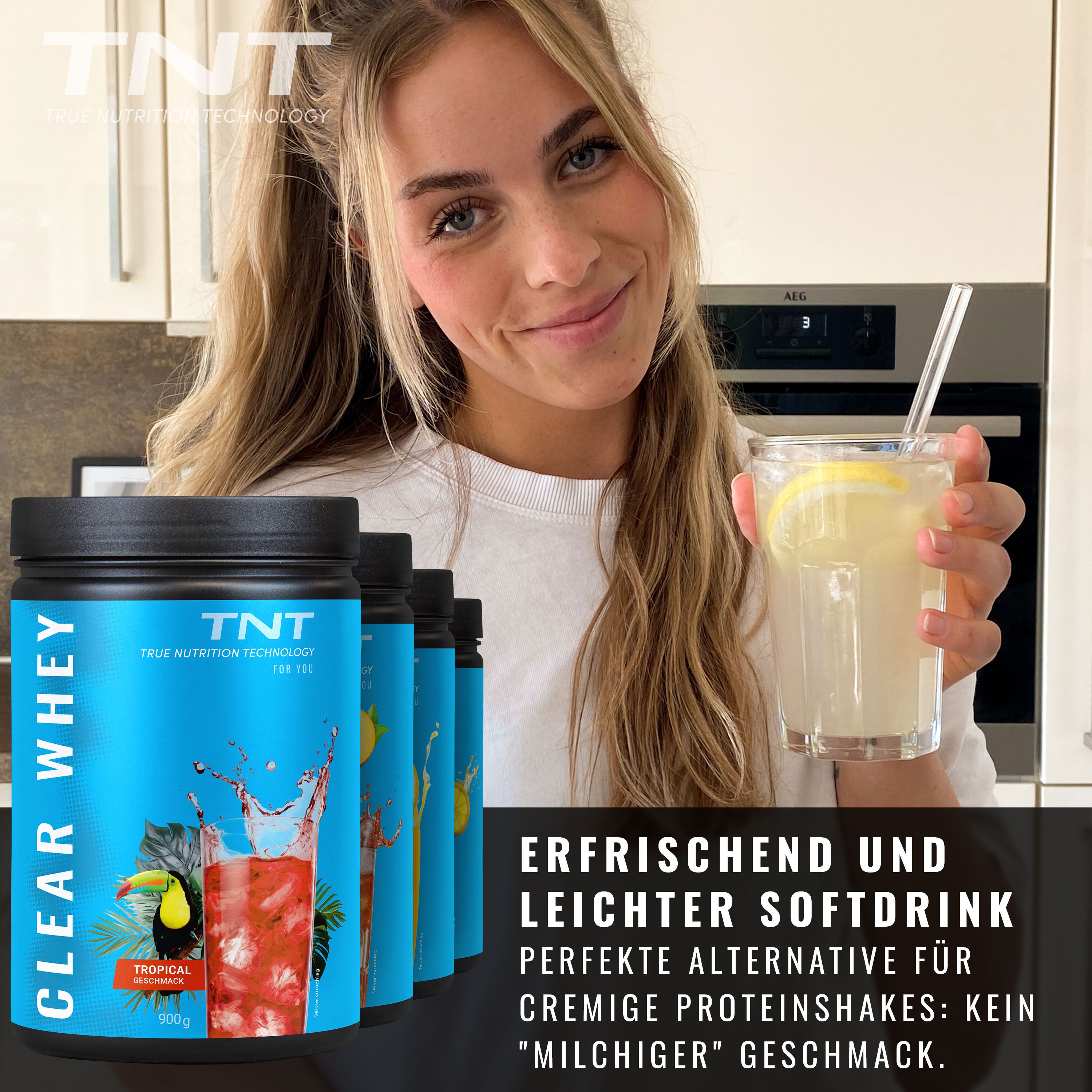 Frau hält ein Glas mit Getränk und Zitrone. Im Hintergrund mehrere Dosen TNT CLEAR WHEY.