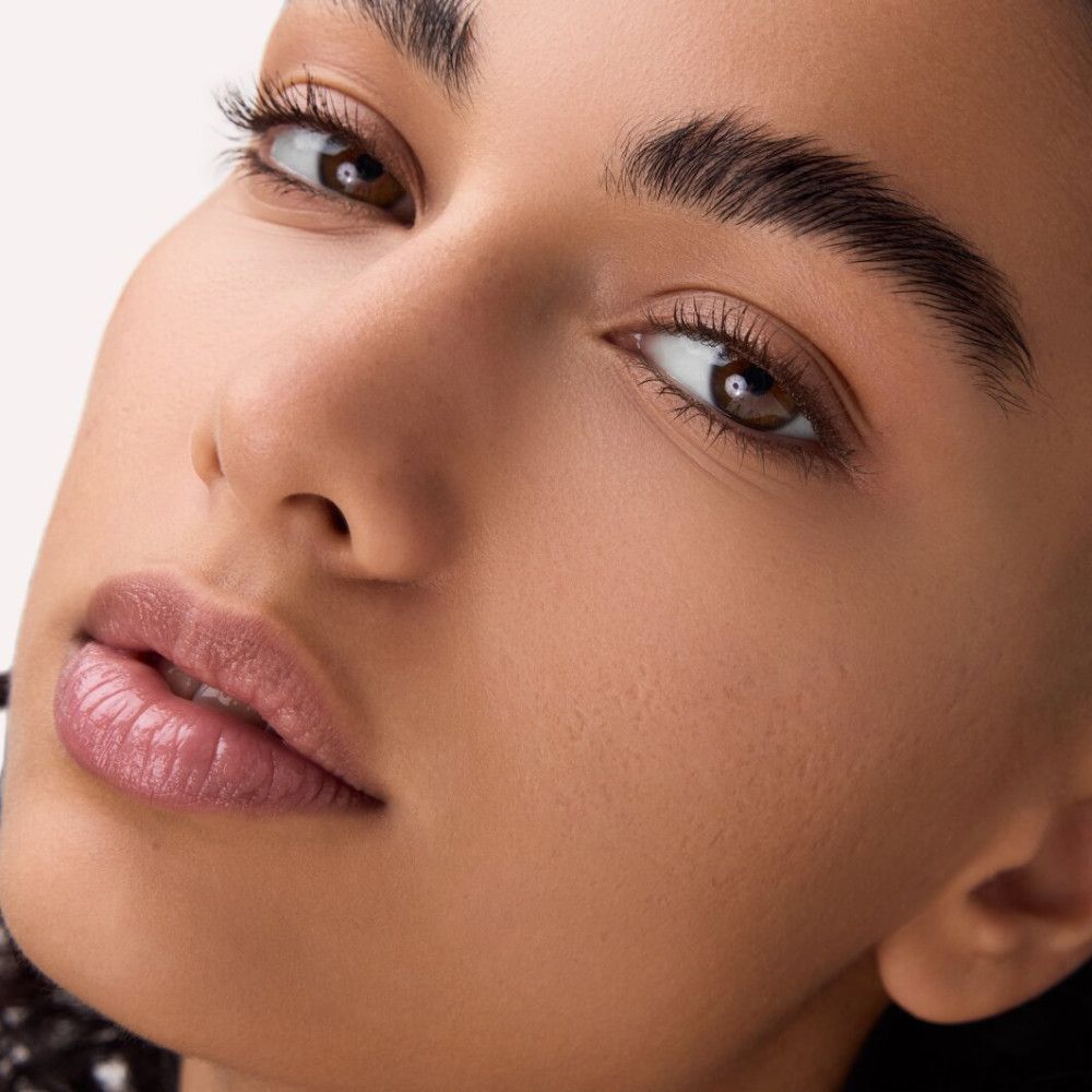 Nahaufnahme eines Gesichts mit Make-up. Fokus auf Augen und Lippen. Hautton und Textur sichtbar.