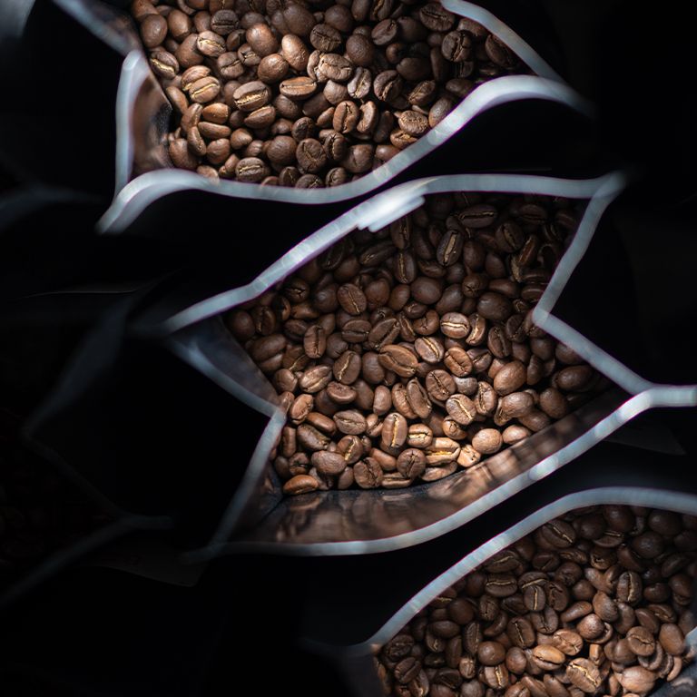 Nahaufnahme von drei geöffneten Kaffeebohnenbeuteln. Kaffeebohnen sind sichtbar.