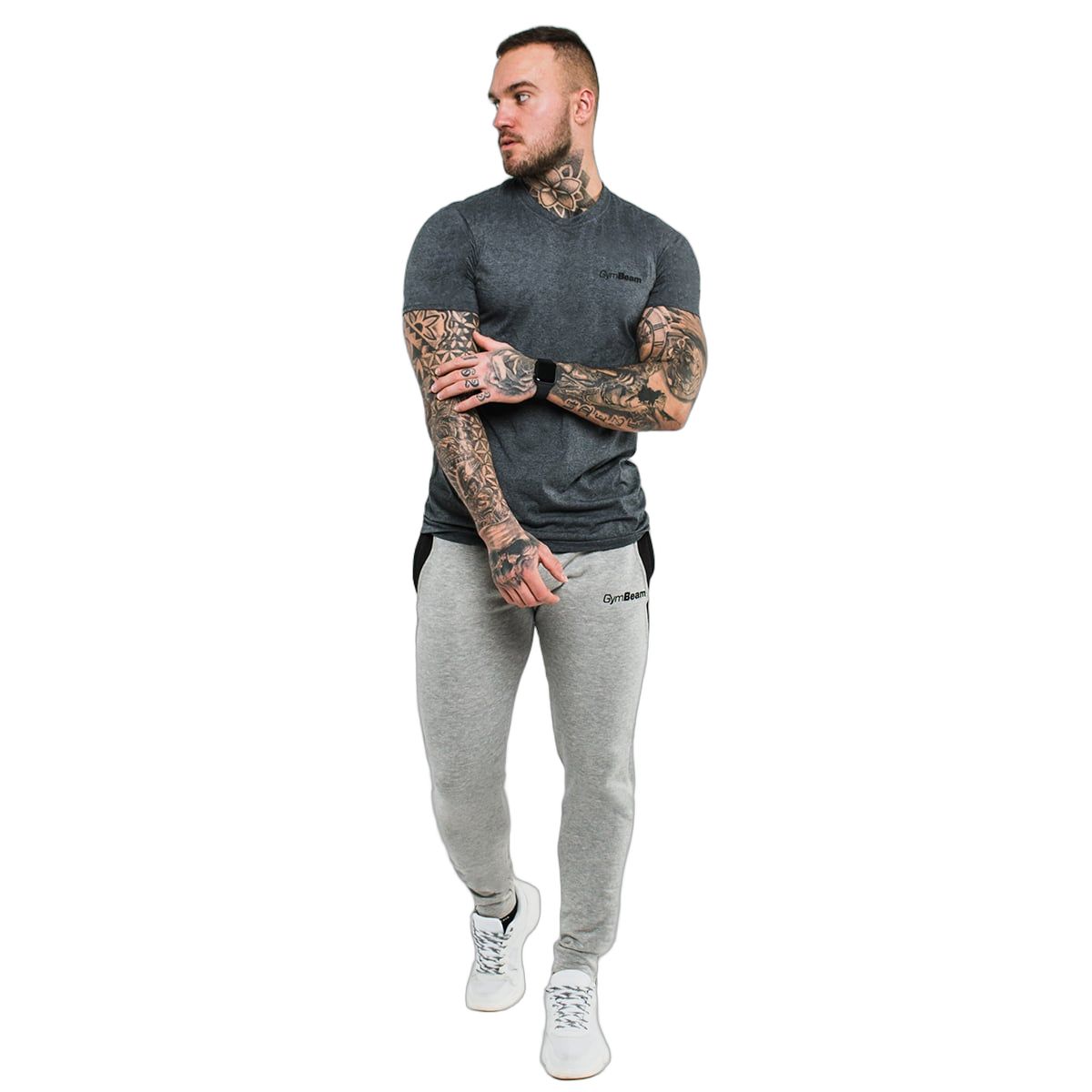 Mann in dunkelgrauem GymBeam T-Shirt und grauer Jogginghose, steht und blickt zur Seite.