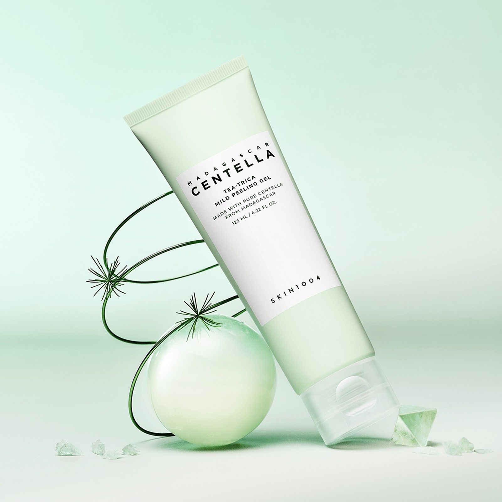 Grüne Tube mit Peeling-Gel, umgeben von grünen Dekorationselementen.
