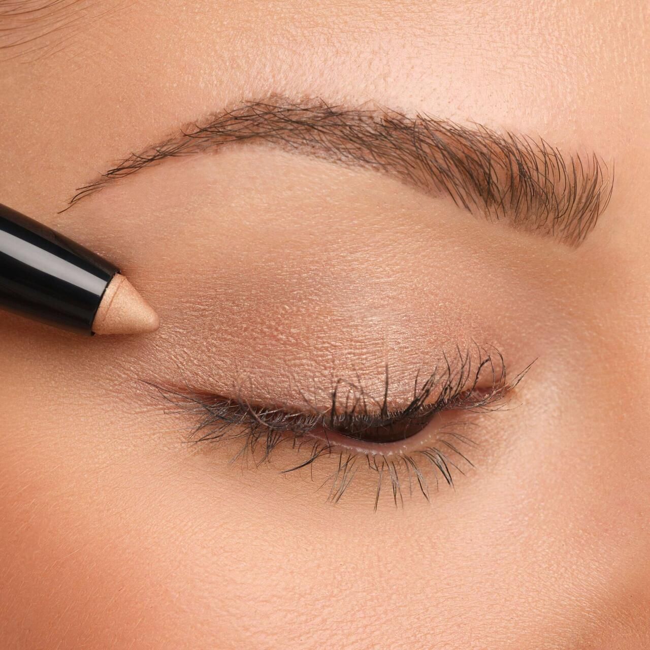 Auge mit aufgetragenem Lidschatten. Artdeco High Performance Eyeshadow Stylo wird verwendet. Beige Farbe.