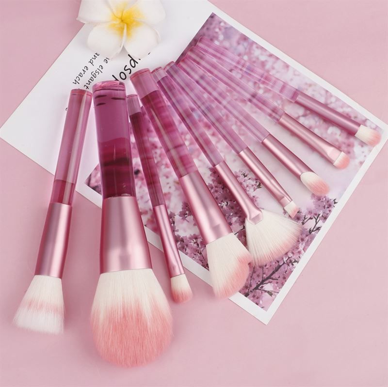 Rosa Make-up-Pinsel-Set. Mehrere Pinsel mit transparenten Griffen und rosa Borsten. Auf rosa Untergrund.