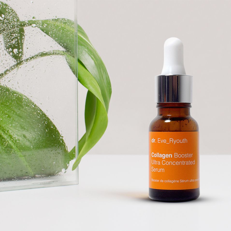 Dr. Eve_Ryouth Kollagenbooster Serum neben grünen Blättern in einem Glasbehälter.