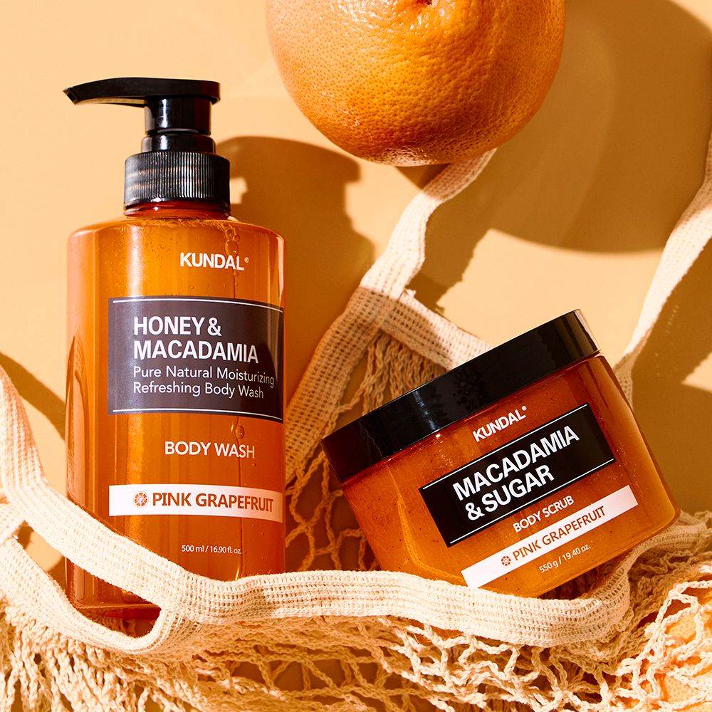 Zwei Produkte: Flasche mit schwarzem Pumpverschluss und Tiegel. Aufschrift: KUNDAL, HONEY & MACADAMIA, BODY WASH und BODY SCRUB.