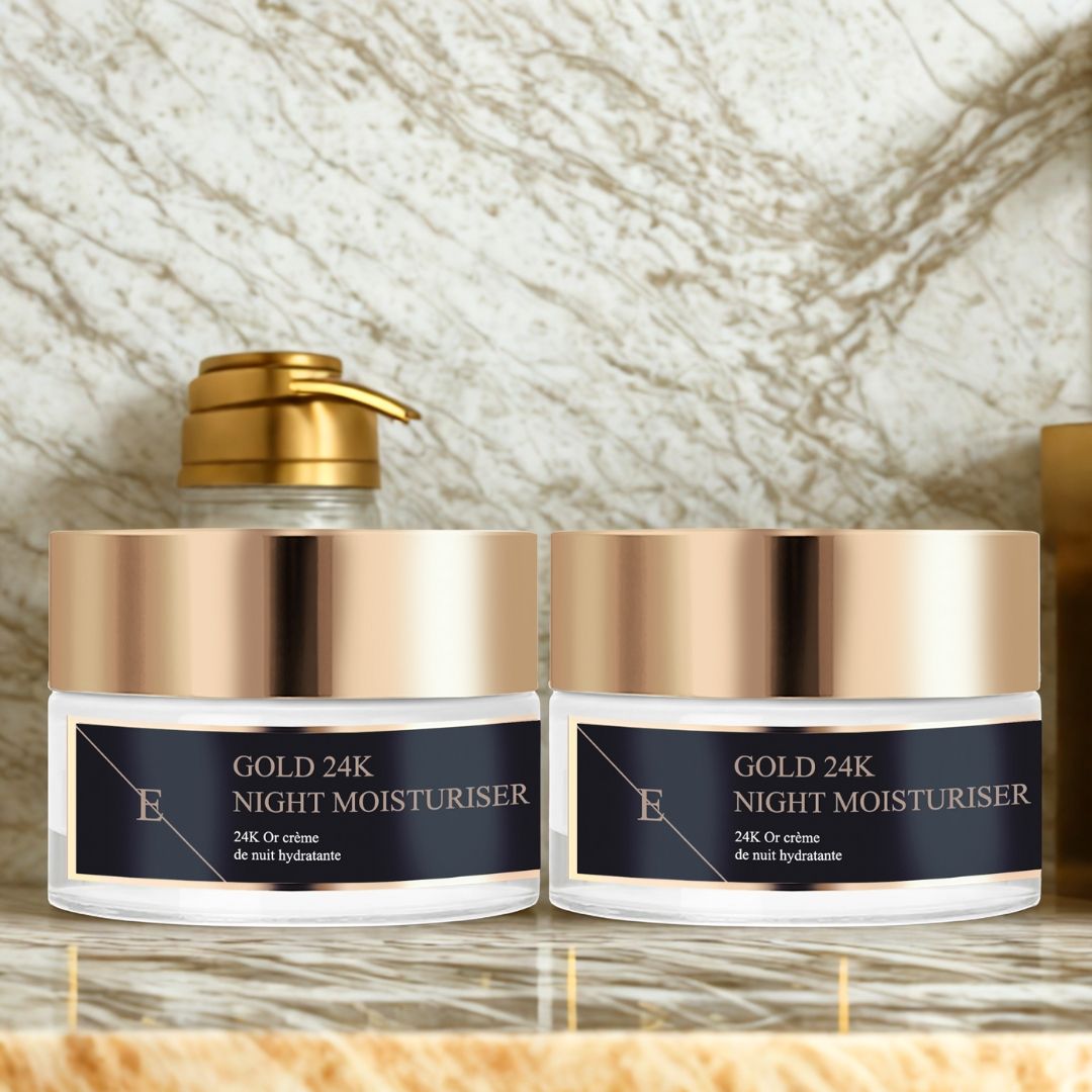 Zwei Tiegel mit goldfarbenen Deckeln. Schwarze Etiketten mit Text: GOLD 24K NIGHT MOISTURISER. Logo "E". Auf Ablage.