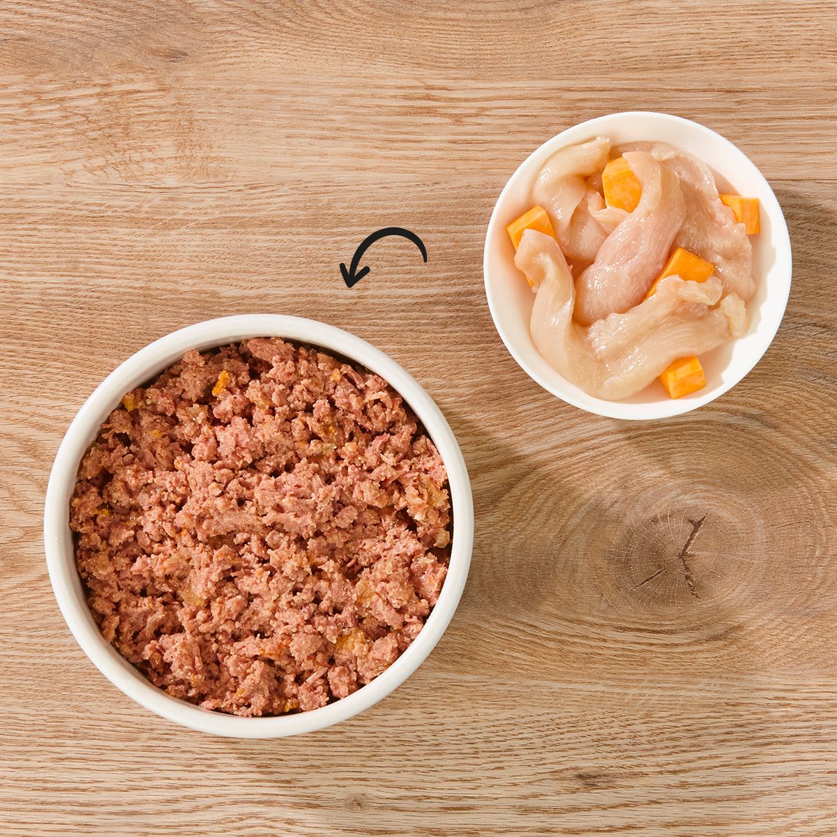 Zwei Schalen mit Hundefutter. Eine Schale enthält zerkleinertes Futter, die andere Hühnchenstücke und Süßkartoffelwürfel.