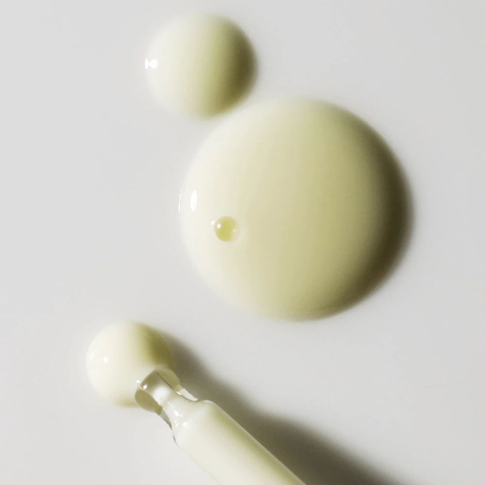 Nahaufnahme von Serumtropfen. Drei Tropfen in verschiedenen Größen und eine Pipette mit Serum.